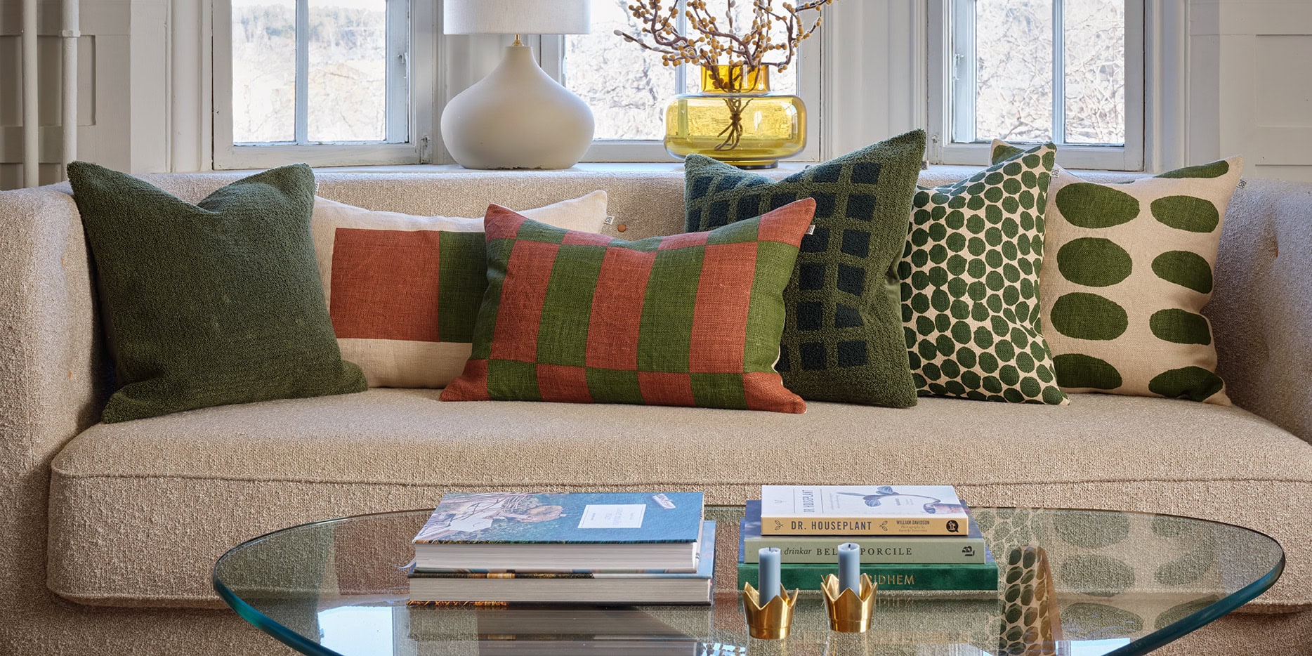 Green and terracotta designer cushions in boucle and linen, on a white sofa