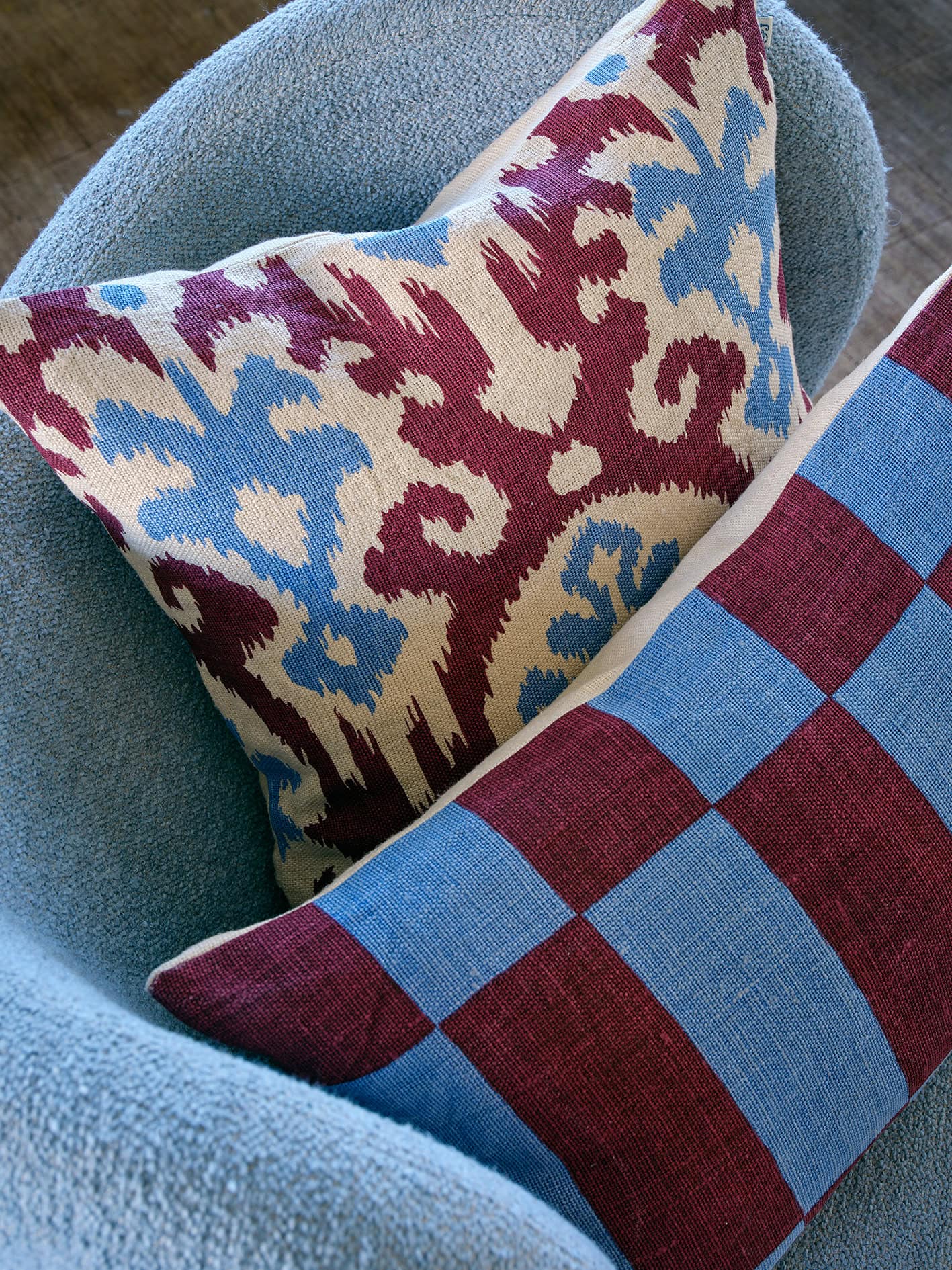 Blue and ruby coloured patterned linen cushion in a blue armchair