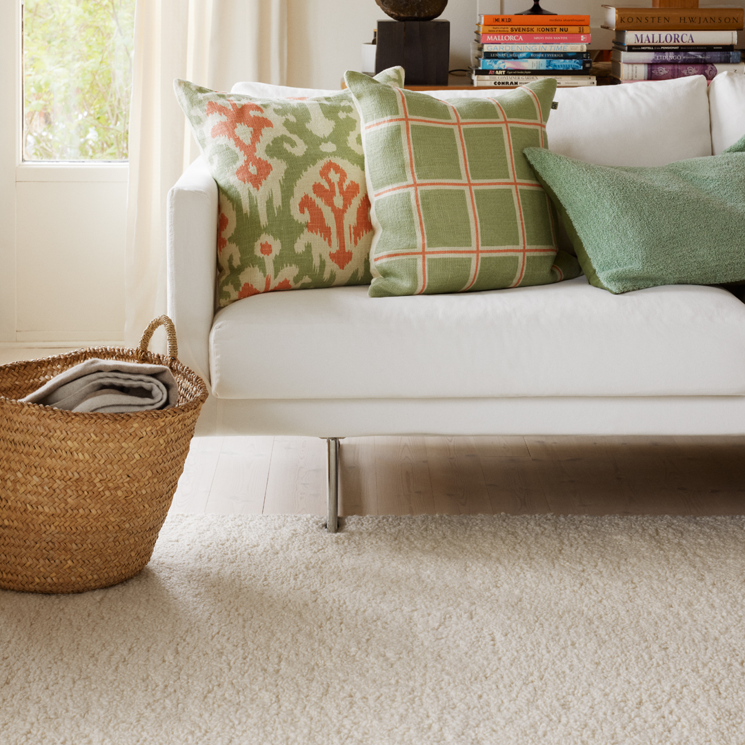 green and pink linen cushions on white sofa with white wool rug