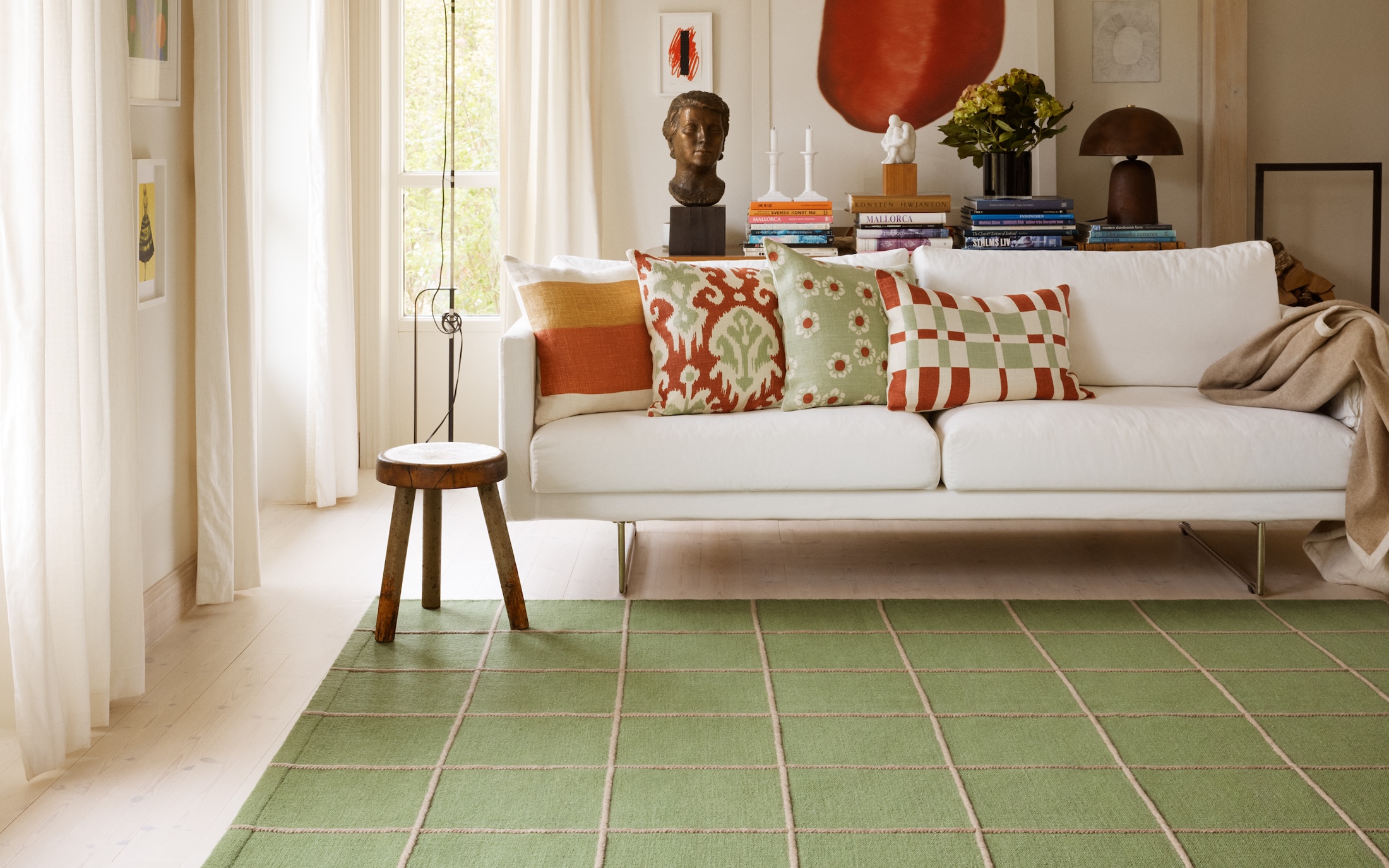 patterned cushions on white sofa with green hand woven wool rug on the floor