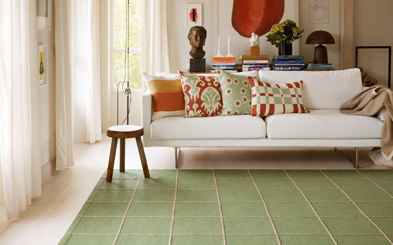 våriga kuddar i grönt och rött på en vit soffa i ett inspirerande vardagsrum